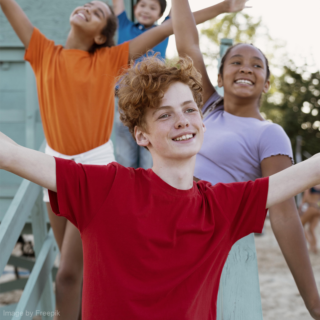 Vier glückliche Kinder stehen auf einer Treppe und haben die Arme wie bei einem Jubel oben.