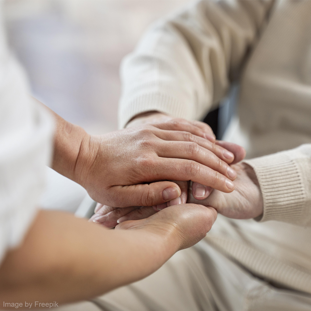Eine Pflegekraft hält die Hände einer älteren Person.